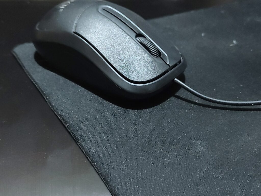A black mouse with a mousepad on it