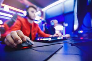 Professional gamer controls computer mouse online game in neon color blur background, soft focus